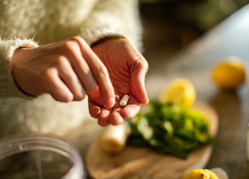 Close up of a Young woman taking a health supplement in the kitchen