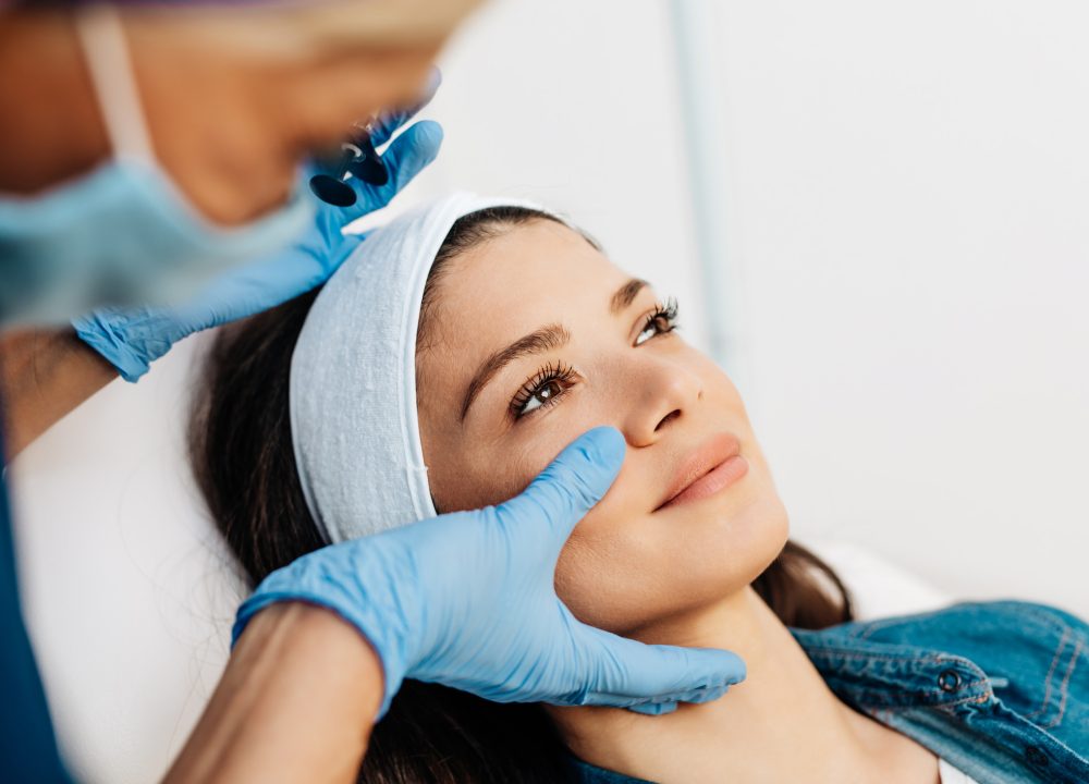 Attractive young woman is getting a rejuvenating facial injections at beauty clinic. The expert beautician is filling female wrinkles by botulinum.